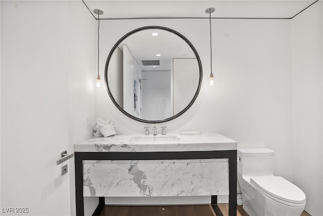 bathroom with visible vents, vanity, toilet, and wood finished floors