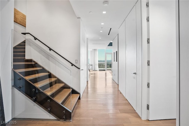 stairway with floor to ceiling windows, wood finished floors, and recessed lighting