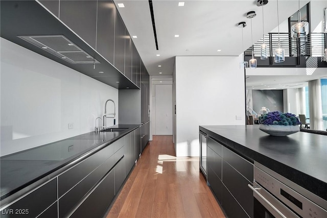 kitchen featuring dark countertops, light wood-style flooring, modern cabinets, and a sink