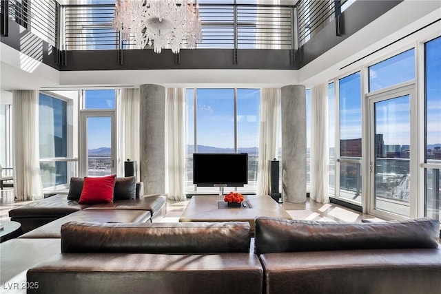 living area featuring plenty of natural light, a towering ceiling, and a notable chandelier