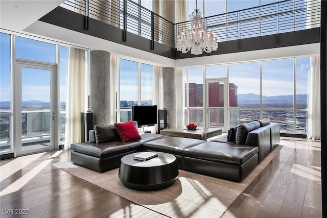 living room with hardwood / wood-style floors, a towering ceiling, and a notable chandelier