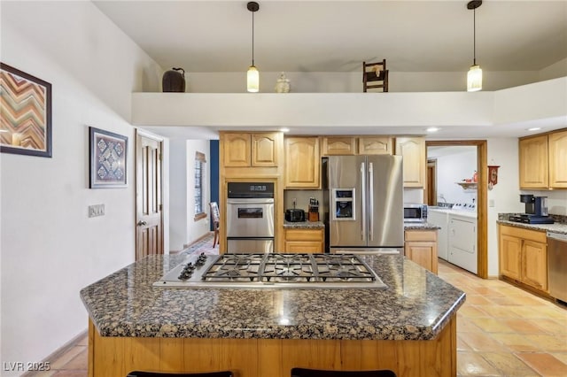 kitchen featuring hanging light fixtures, a center island, appliances with stainless steel finishes, and independent washer and dryer