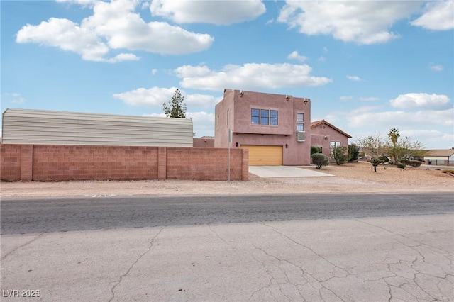 view of front of property with a garage, concrete driveway, fence, and stucco siding