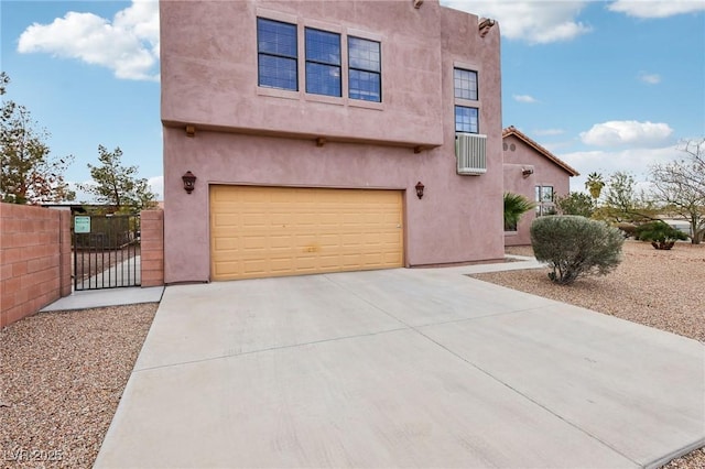 southwest-style home with concrete driveway, fence, a gate, and stucco siding