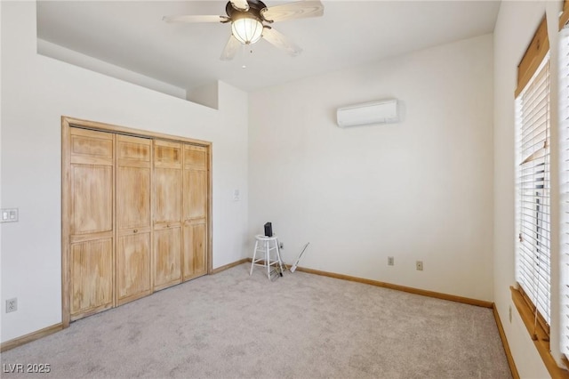 unfurnished bedroom featuring an AC wall unit, light colored carpet, and baseboards