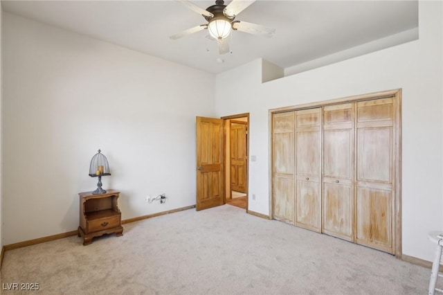 unfurnished bedroom featuring light carpet, a closet, a ceiling fan, and baseboards