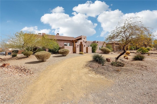 view of front facade with driveway, a chimney, and stucco siding