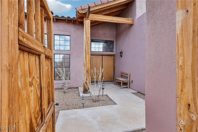 view of exterior entry featuring a patio area and stucco siding