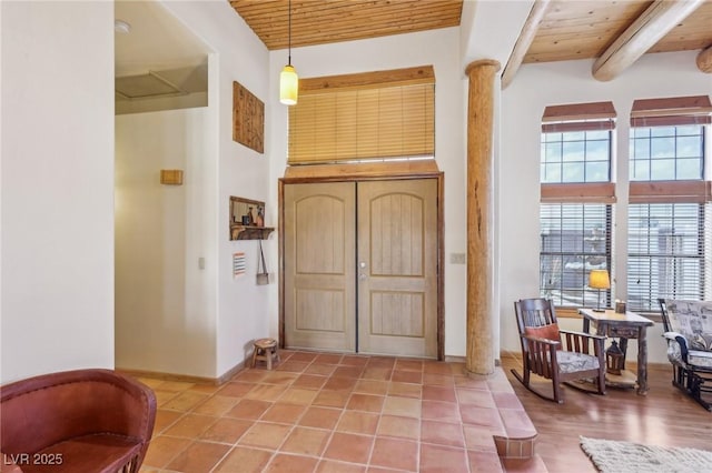 tiled entrance foyer featuring a healthy amount of sunlight, wooden ceiling, decorative columns, and beam ceiling