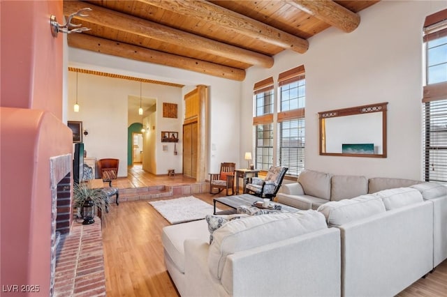 living area featuring arched walkways, wood ceiling, beam ceiling, and wood finished floors