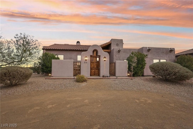 view of front facade featuring a fenced front yard, a gate, a tiled roof, and stucco siding