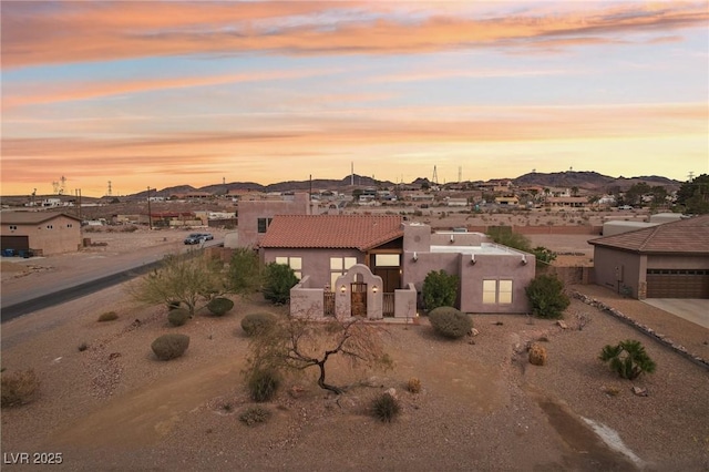 view of front of home with a garage, driveway, a tile roof, and stucco siding