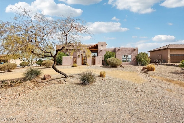 adobe home featuring a gate, fence, and stucco siding