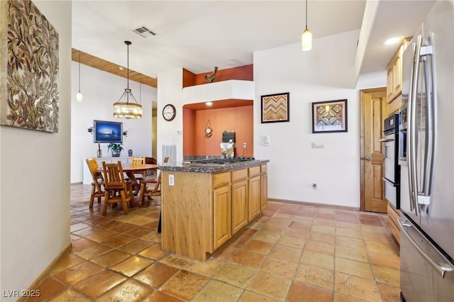 kitchen featuring visible vents, appliances with stainless steel finishes, stone tile flooring, and decorative light fixtures