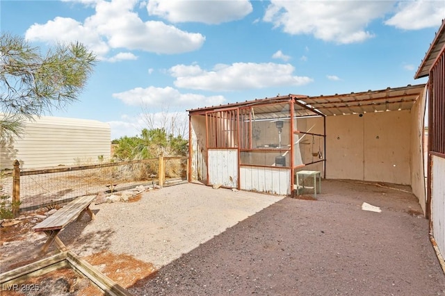 view of outdoor structure with fence and an outbuilding