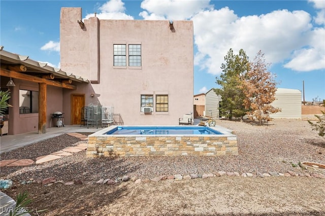 back of property with a patio and stucco siding