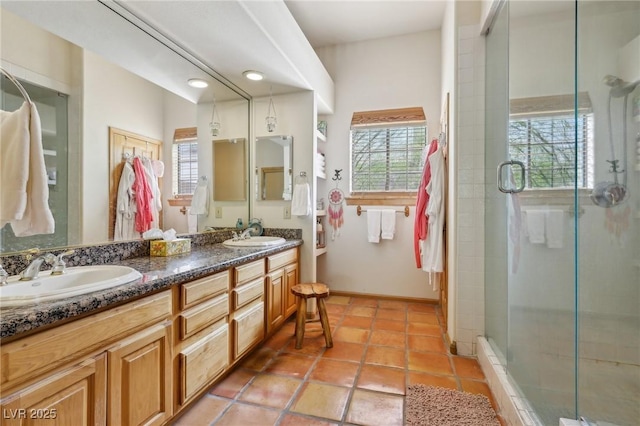 full bathroom featuring a stall shower, a sink, baseboards, and double vanity