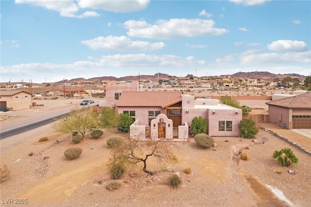 view of front of home with a mountain view, a garage, fence, driveway, and stucco siding