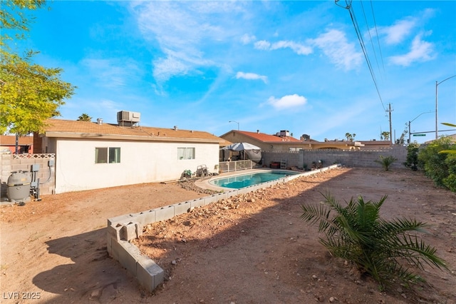 rear view of house with central AC unit, a fenced in pool, a fenced backyard, a patio area, and stucco siding