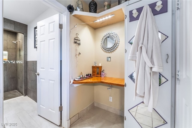 interior space featuring tile patterned flooring, a tile shower, and baseboards