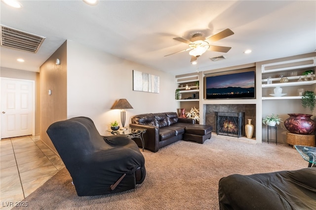 living area featuring a lit fireplace, carpet, visible vents, and built in features