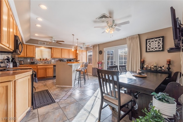 kitchen featuring visible vents, a breakfast bar area, tasteful backsplash, and french doors