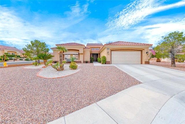 mediterranean / spanish-style home featuring driveway, an attached garage, a tiled roof, and stucco siding