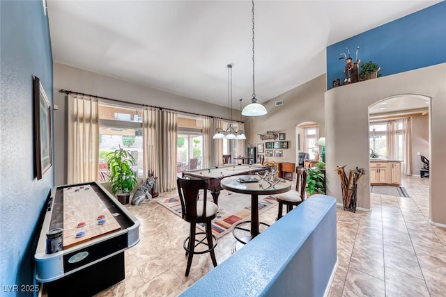 game room with visible vents, a high ceiling, arched walkways, and baseboards