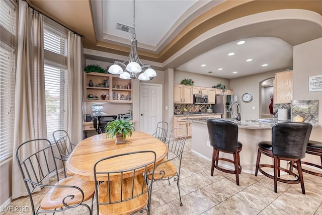 dining space with a chandelier, arched walkways, recessed lighting, visible vents, and a raised ceiling