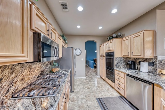 kitchen featuring tasteful backsplash, visible vents, arched walkways, stainless steel appliances, and light brown cabinets