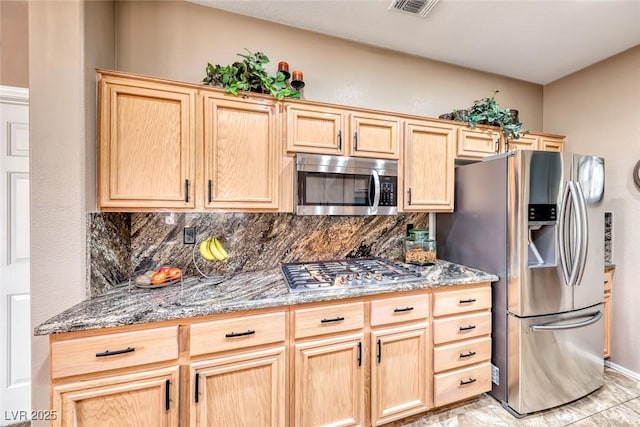 kitchen featuring stainless steel appliances, light brown cabinetry, and tasteful backsplash