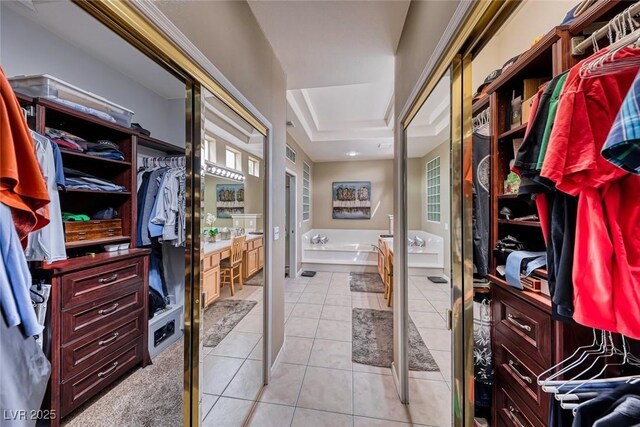 walk in closet with light tile patterned floors and a tray ceiling