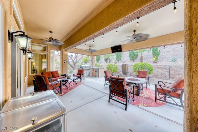 view of patio with an outdoor kitchen, area for grilling, an outdoor living space with a fire pit, and a ceiling fan