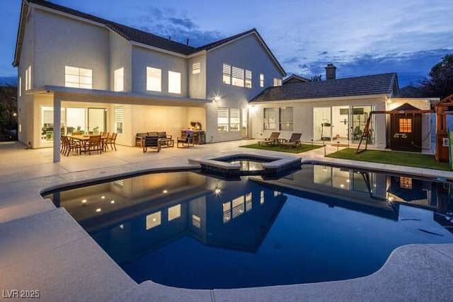 rear view of house with a pool with connected hot tub, a patio, and stucco siding