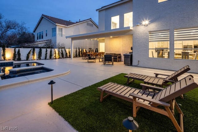 exterior space with an in ground hot tub, a patio, and stucco siding