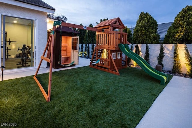 view of jungle gym with a lawn and fence