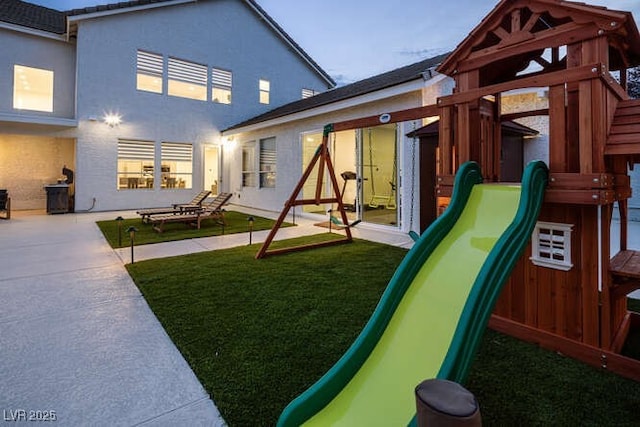 view of playground with a yard and a patio area