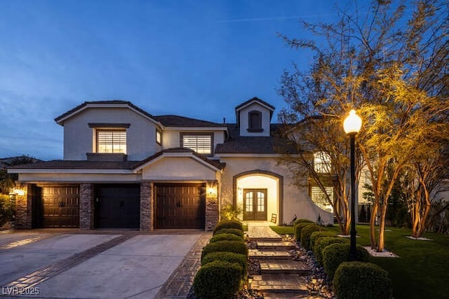 view of front of house with a garage, concrete driveway, french doors, and stucco siding