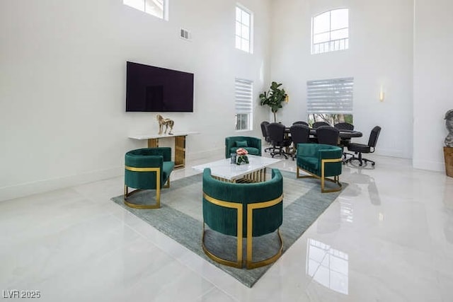 living room with marble finish floor, a high ceiling, visible vents, and baseboards