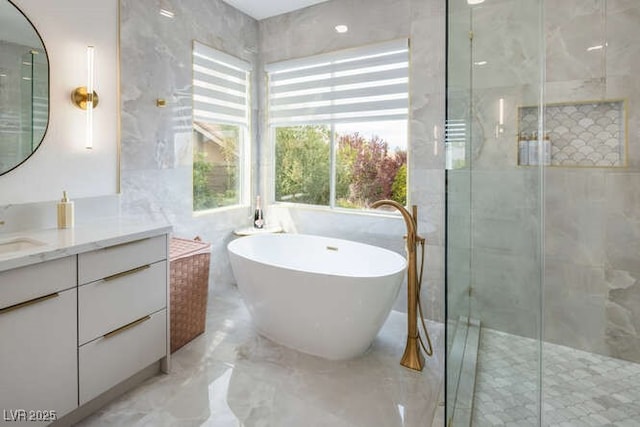 bathroom featuring marble finish floor, vanity, a soaking tub, and a stall shower