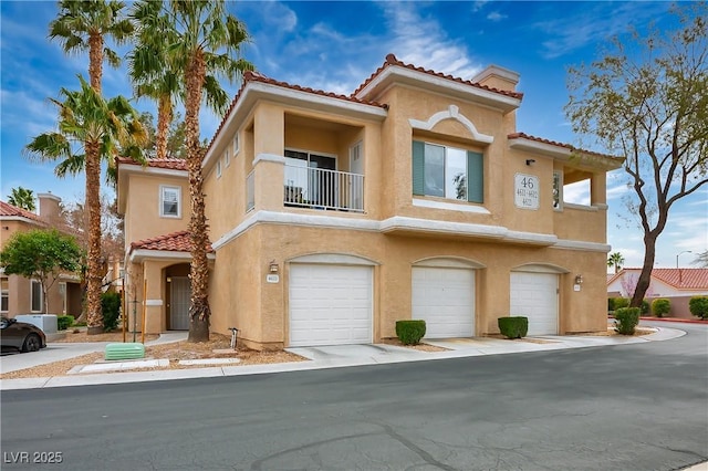 view of front facade featuring a garage, a balcony, a tile roof, and stucco siding