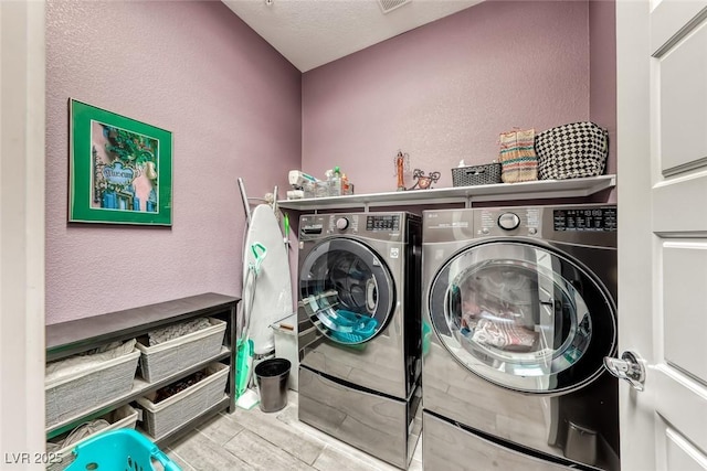 laundry area featuring a textured wall, laundry area, washing machine and dryer, and visible vents