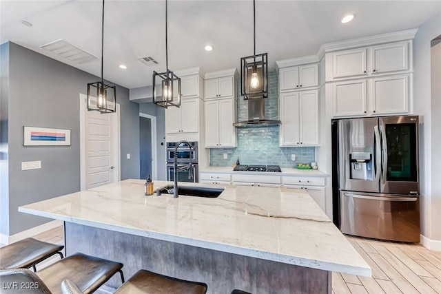 kitchen featuring visible vents, decorative backsplash, stainless steel appliances, light wood-style floors, and a kitchen bar