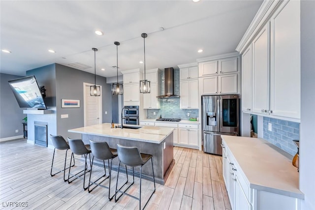 kitchen featuring a breakfast bar, a fireplace, backsplash, appliances with stainless steel finishes, and wall chimney exhaust hood