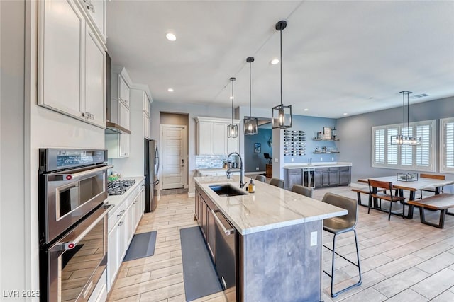 kitchen with tasteful backsplash, a center island with sink, stainless steel appliances, a kitchen bar, and a sink