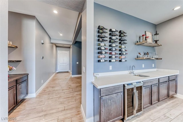 bar featuring light wood-style flooring, recessed lighting, beverage cooler, a sink, and indoor wet bar