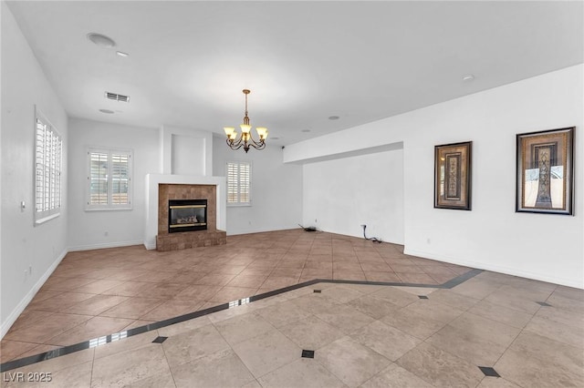 unfurnished living room featuring baseboards, visible vents, an inviting chandelier, tile patterned flooring, and a tiled fireplace