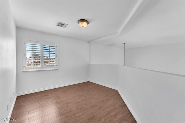 unfurnished room with wood finished floors, visible vents, and baseboards