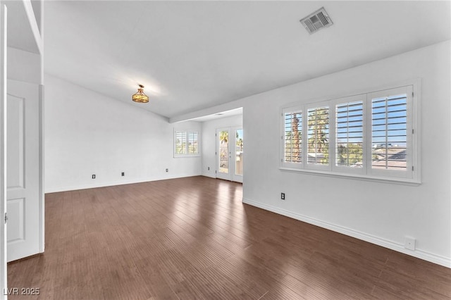 unfurnished living room featuring visible vents, baseboards, and dark wood-style floors