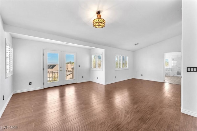 empty room featuring visible vents, baseboards, wood finished floors, and vaulted ceiling